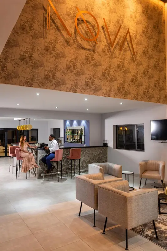 Un bar moderne avec des tabourets et des fauteuils confortables.