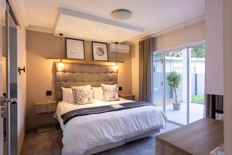 Une chambre lumineuse avec un grand lit et un accès à une terrasse.