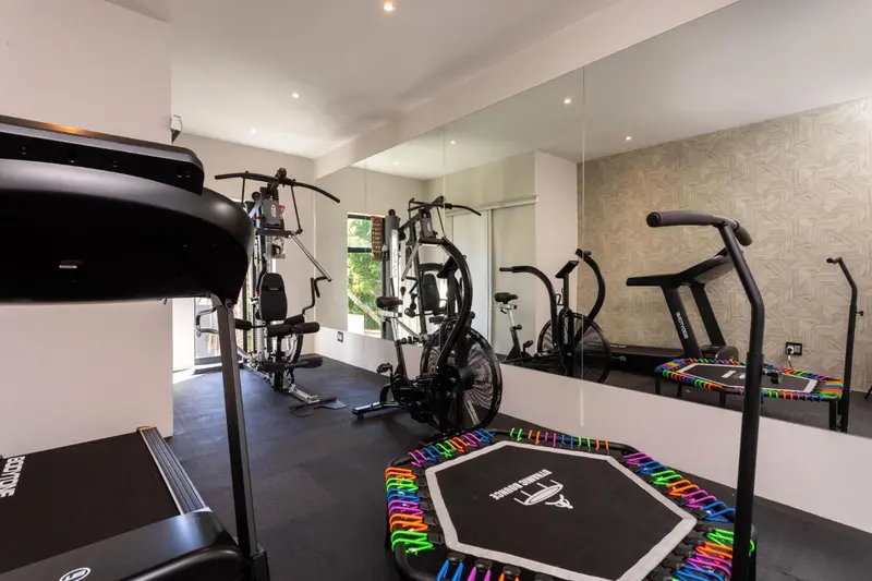 Une salle de sport lumineuse avec plusieurs appareils de fitness et des miroirs.