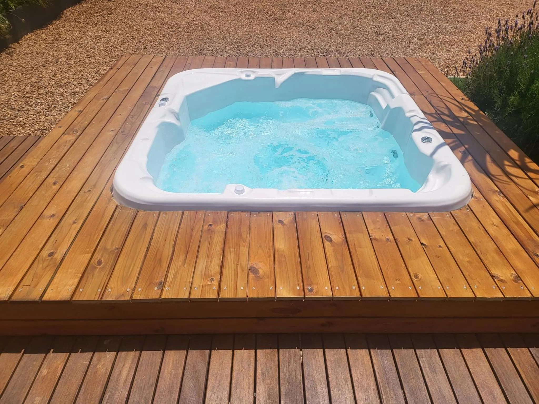 Jacuzzi extérieur sur une terrasse en bois.