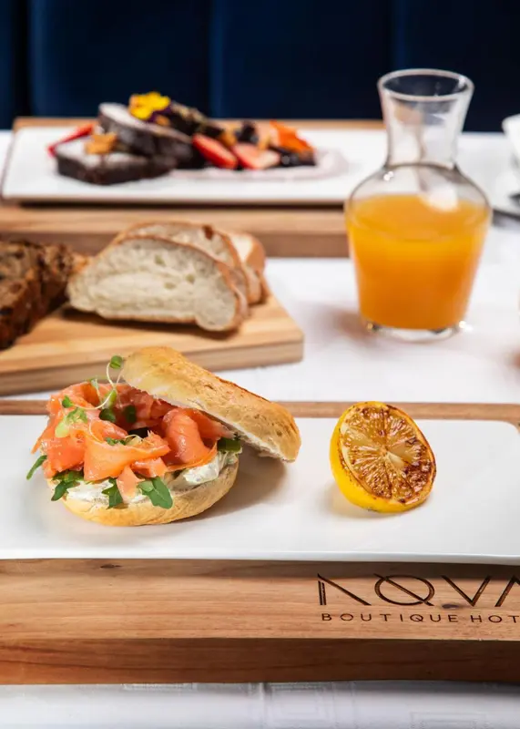 Une table en bois présente un petit-déjeuner avec des viennoiseries, des fruits et une boisson orangée.