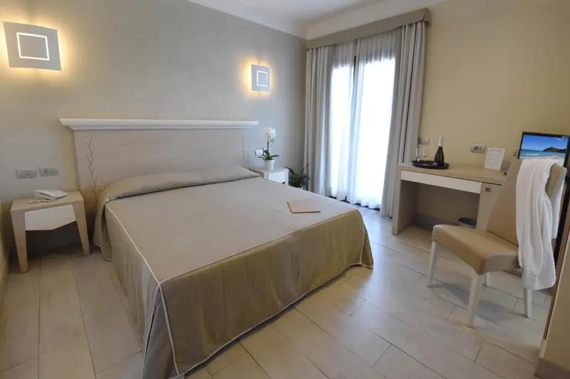 Chambre lumineuse avec un grand lit et un bureau.