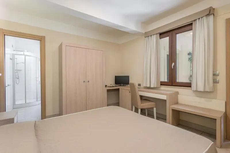 Une chambre lumineuse avec un lit, un bureau et une salle de bain attenante.