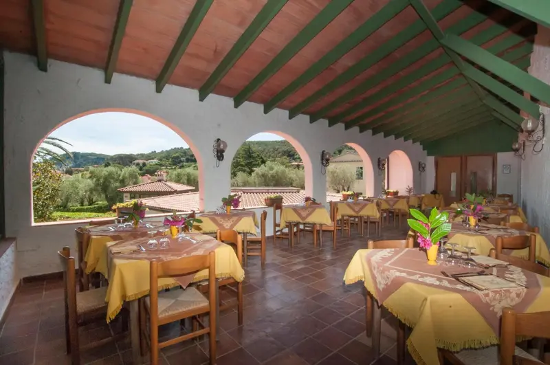 Terrasse ombragée avec tables dressées pour un repas en extérieur.