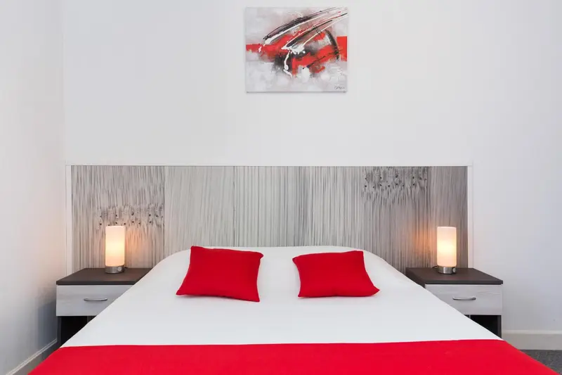 Une chambre avec un grand lit recouvert d'une literie blanche et rouge.