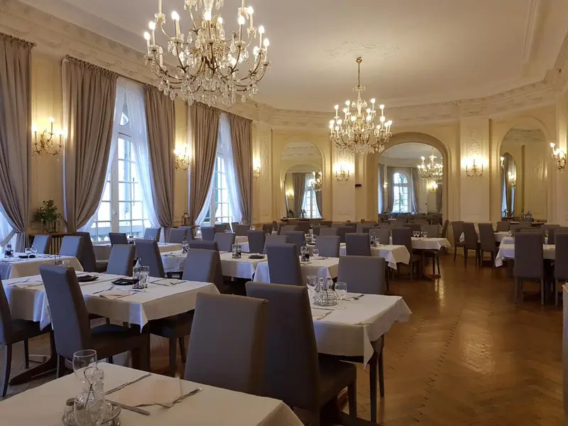 Une salle lumineuse avec des tables dressées pour un repas.