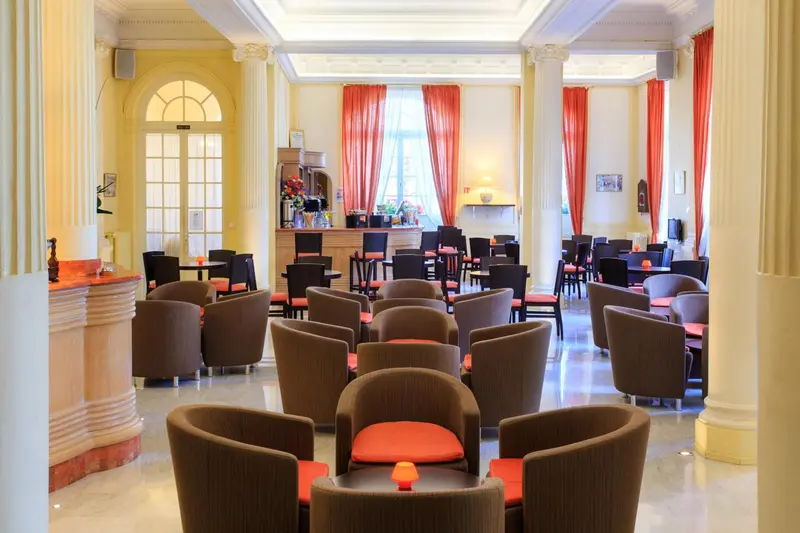 Une salle lumineuse avec des fauteuils et des tables basses près d'un comptoir.
