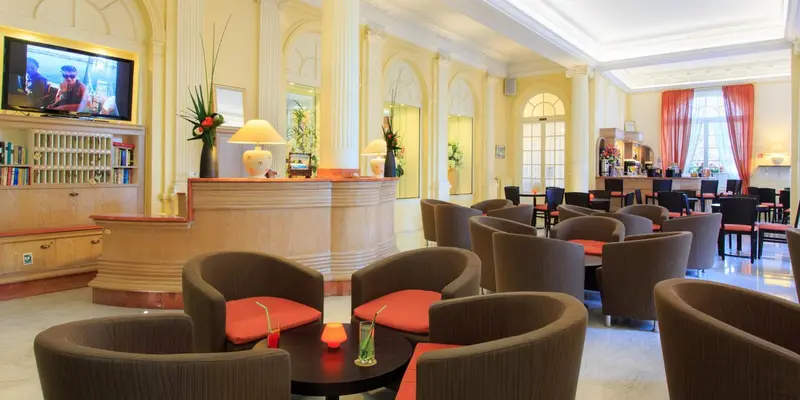 Un espace de détente avec des fauteuils et des tables basses dans un hall d'hôtel.