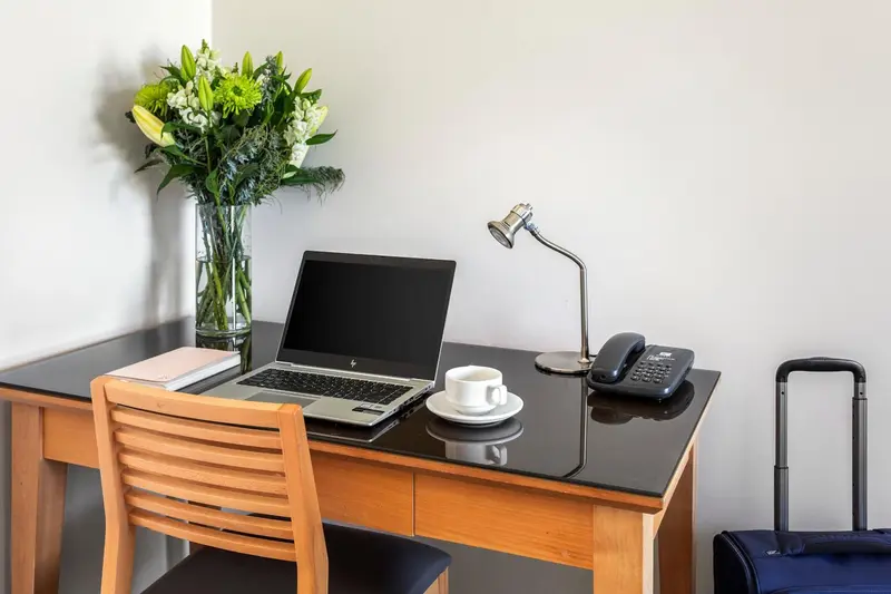 Un bureau en bois avec un ordinateur portable, une tasse et une lampe.