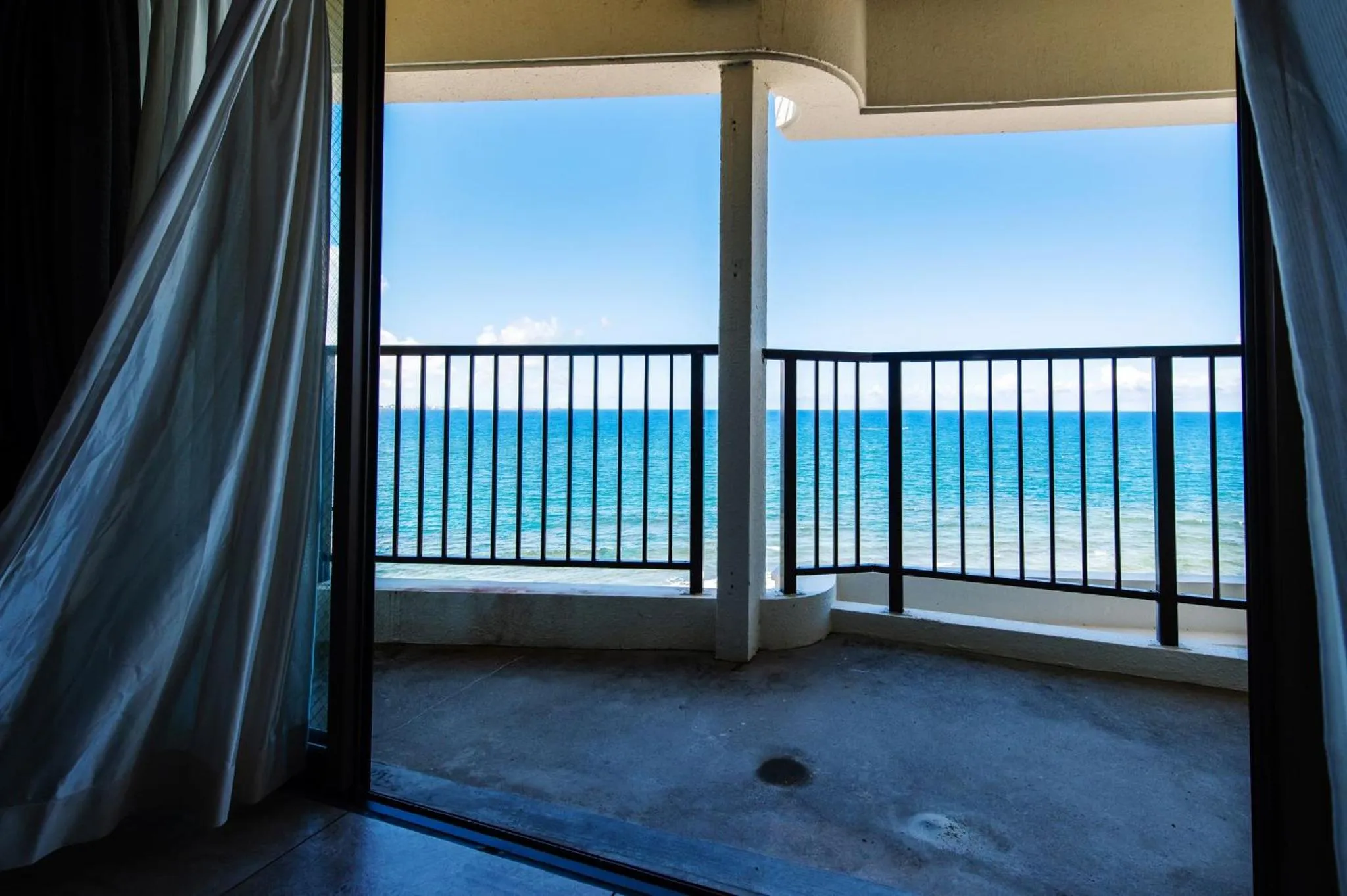 Vue sur la mer depuis un balcon ombragé.