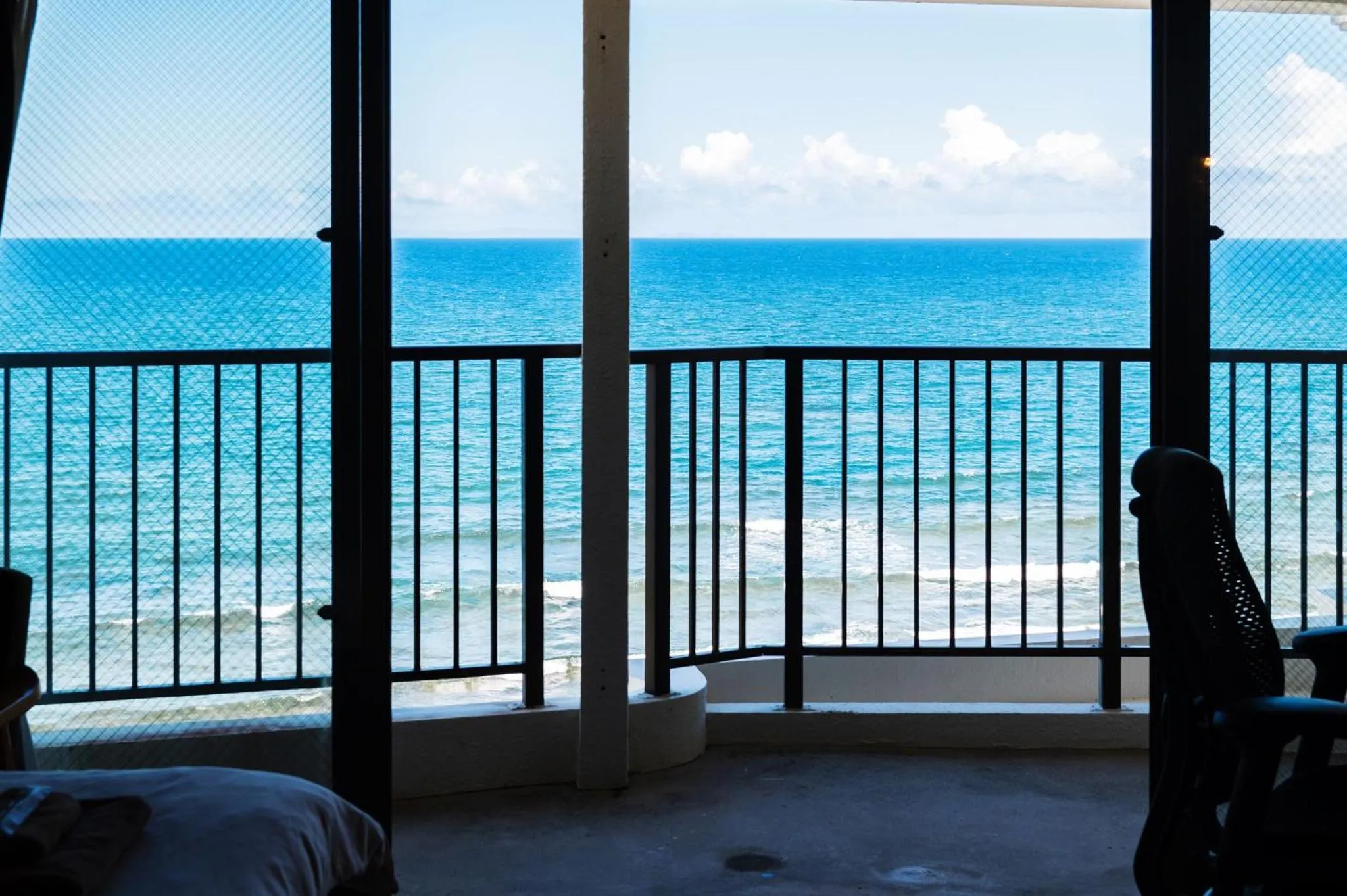Vue sur la mer depuis un balcon avec une rambarde sombre.