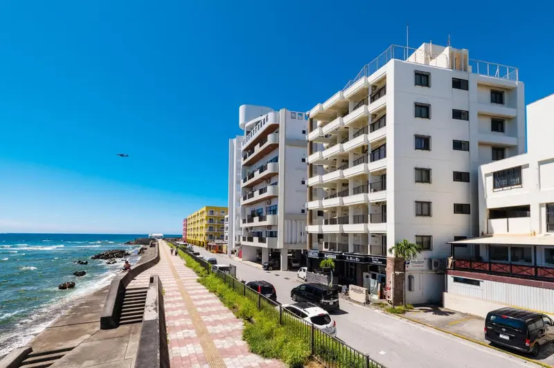 Bâtiment blanc à plusieurs étages avec des balcons donnant sur la mer.