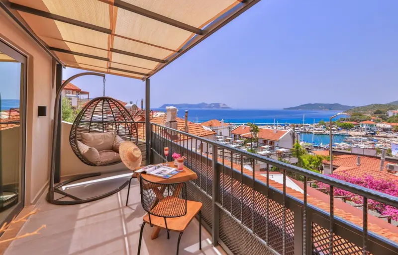Une terrasse avec mobilier d'extérieur offre une vue sur la mer et un port.
