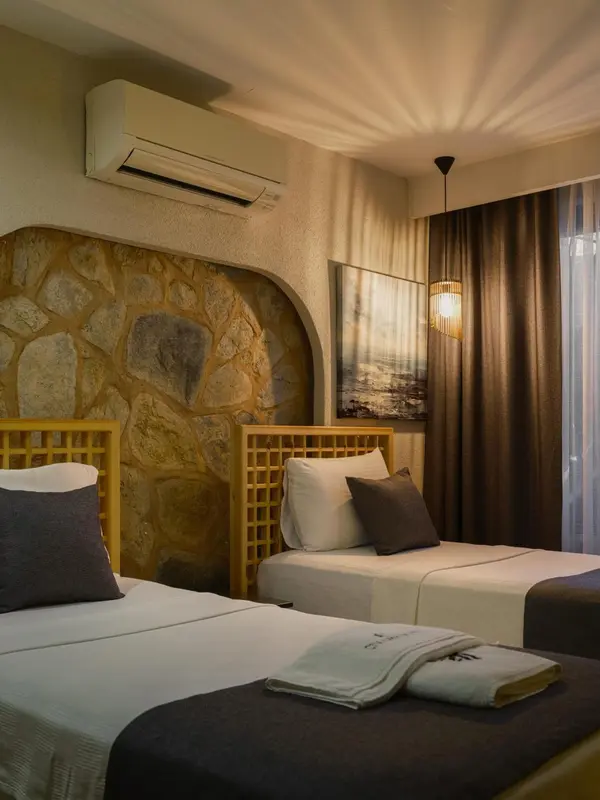 Une chambre avec deux lits simples et un mur en pierre.