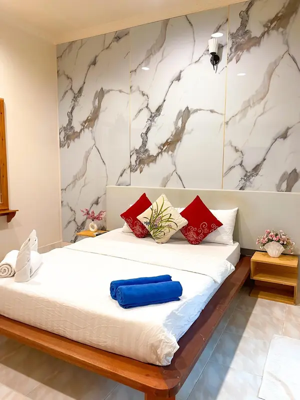 Une chambre lumineuse avec un grand lit recouvert de draps blancs et de coussins rouges.