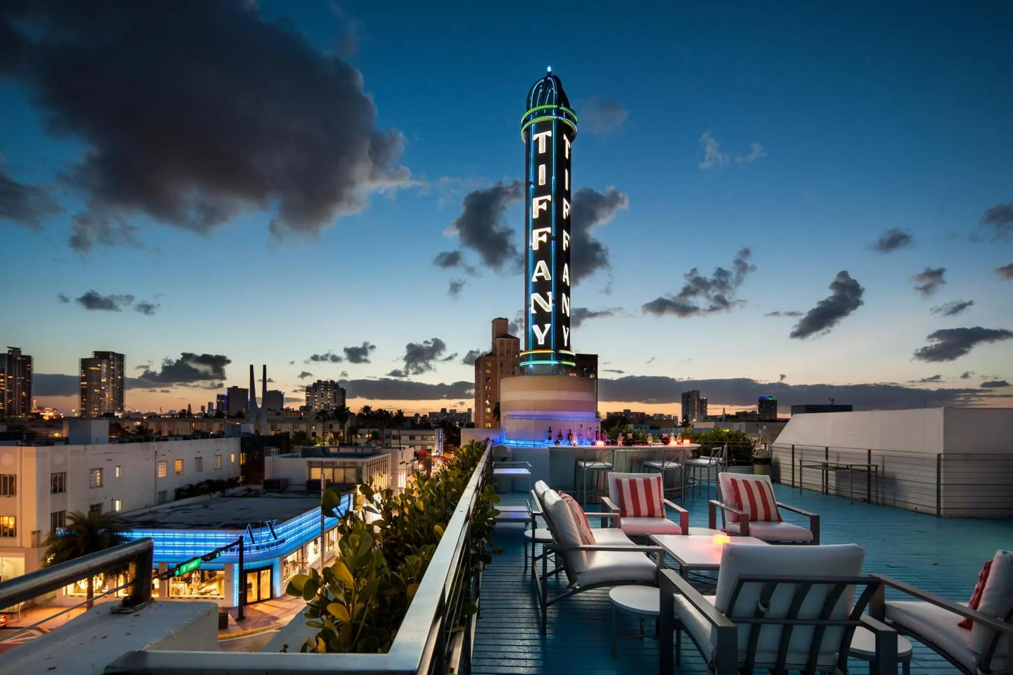 Terrasse aménagée avec mobilier de détente et vue sur la ville illuminée au crépuscule.