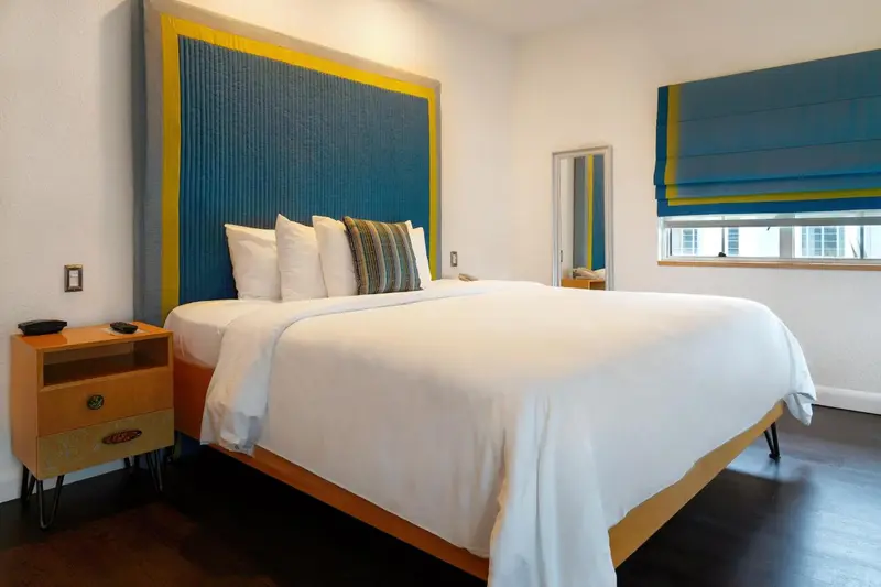 Une chambre lumineuse avec un grand lit recouvert d'une couette blanche et d'oreillers.