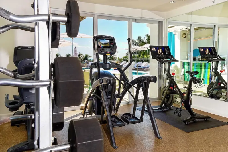 Une salle de sport lumineuse avec des équipements de fitness face à une piscine.