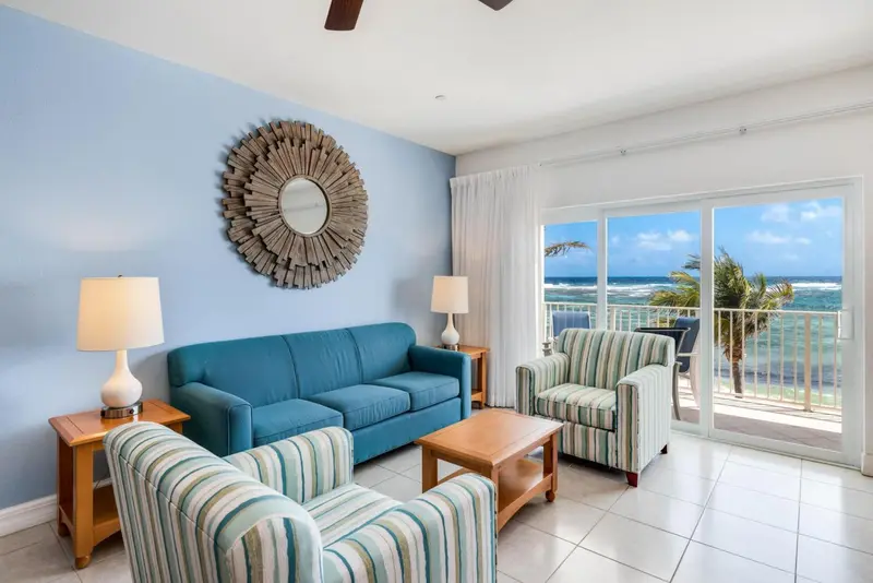 Un salon lumineux avec canapé et fauteuils, donnant sur une vue mer.