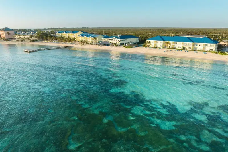 Vue aérienne d'un complexe hôtelier bordant une plage de sable blanc et une mer turquoise.