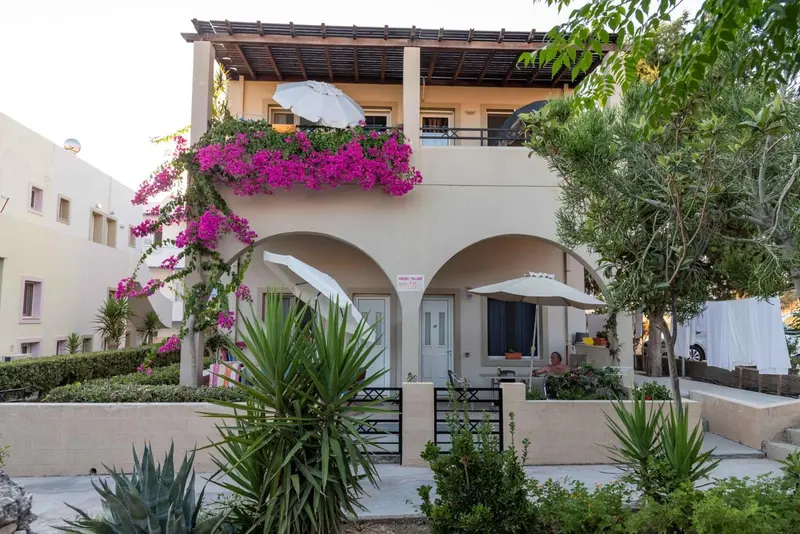 Façade d'un bâtiment blanc orné de fleurs et de végétation.
