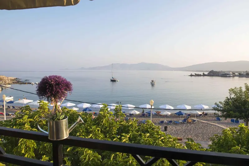 Vue sur une plage et la mer depuis une terrasse ensoleillée.