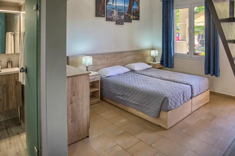Une chambre lumineuse avec un lit double et un accès à une salle de bain.