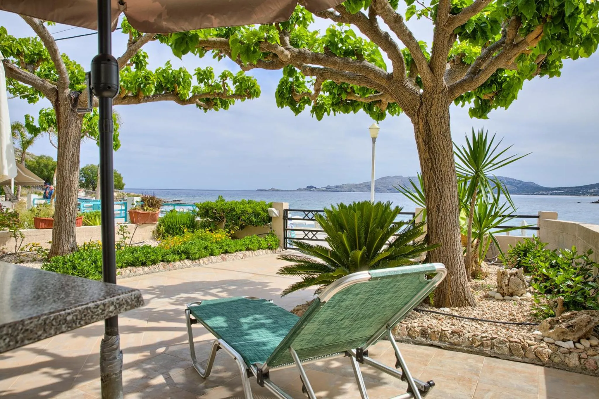 Une terrasse ombragée offre une vue sur la mer et la végétation.
