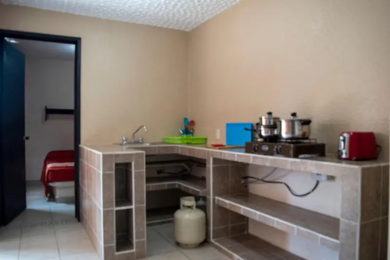 Une kitchenette avec un évier, une gazinière et des ustensiles de cuisine.