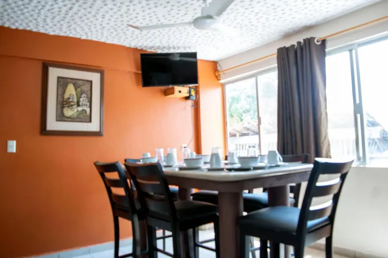 Une table est mise pour le repas dans une salle lumineuse aux murs orange.