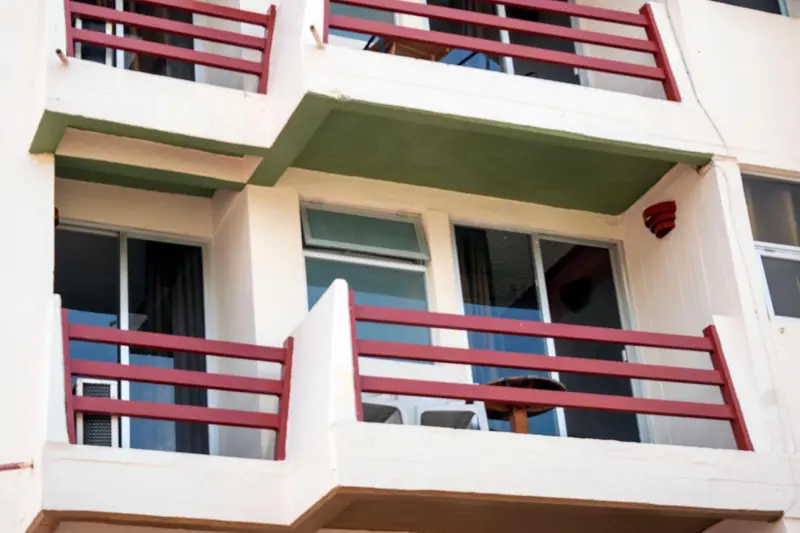 Balcons avec garde-corps rouge et vue sur des climatiseurs.