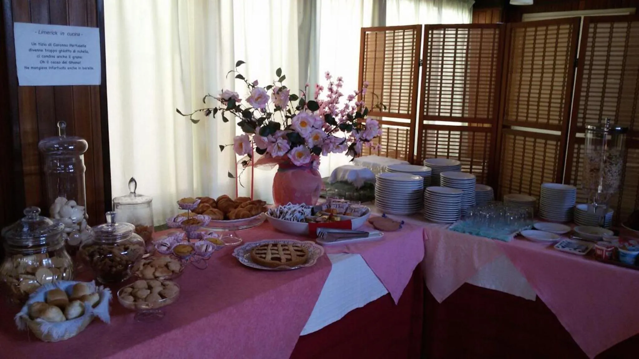 Un buffet propose des pâtisseries et des boissons sur une table recouverte d'une nappe rose.
