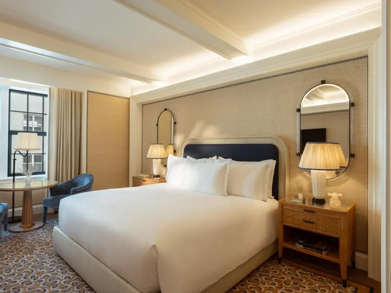 Une chambre lumineuse avec un grand lit et un miroir décoratif.