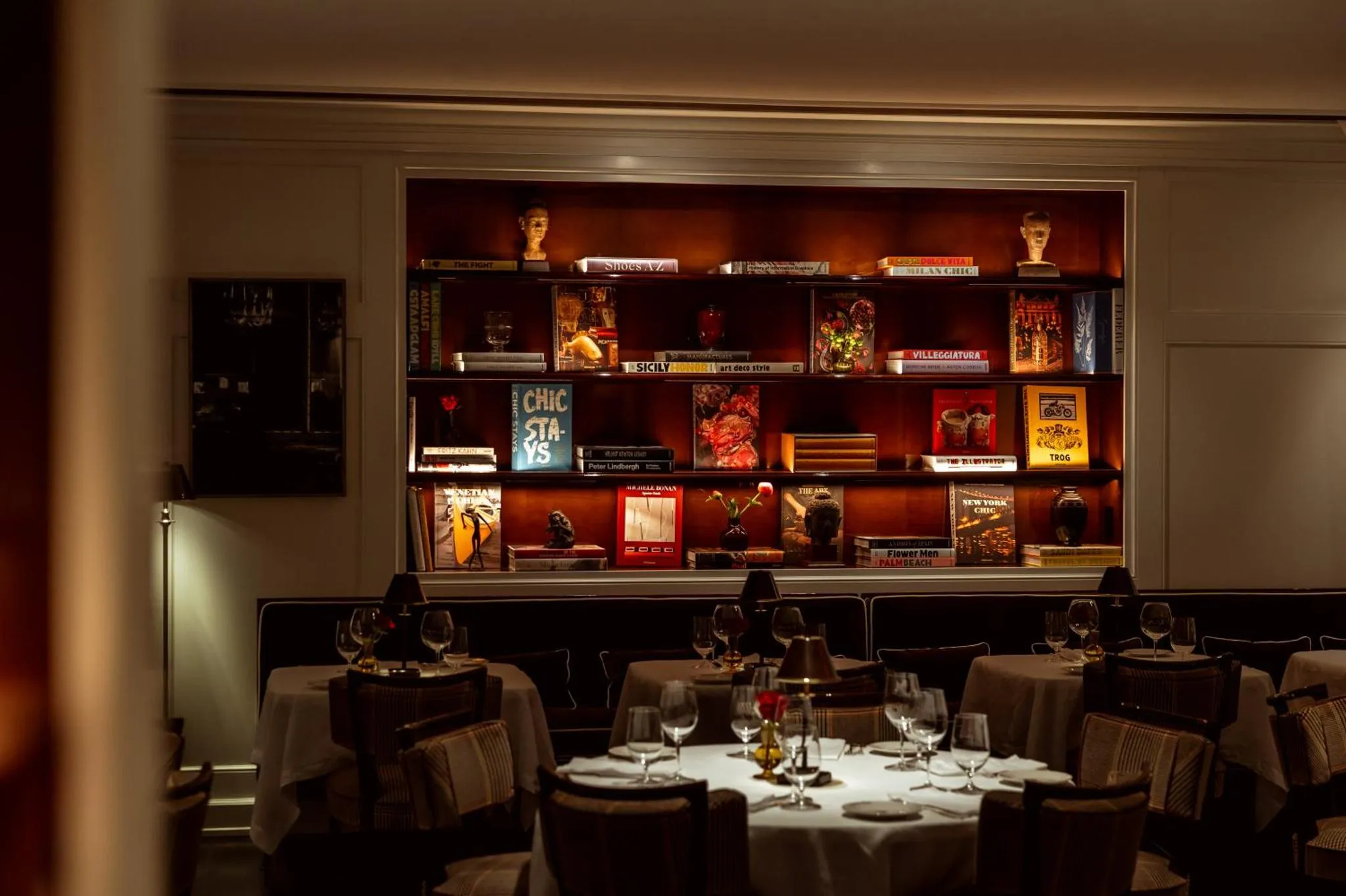 Une salle à manger avec des tables dressées et une bibliothèque décorative.