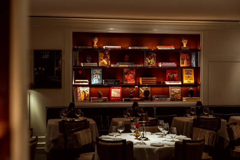 Une salle à manger avec des tables dressées et une bibliothèque décorative.
