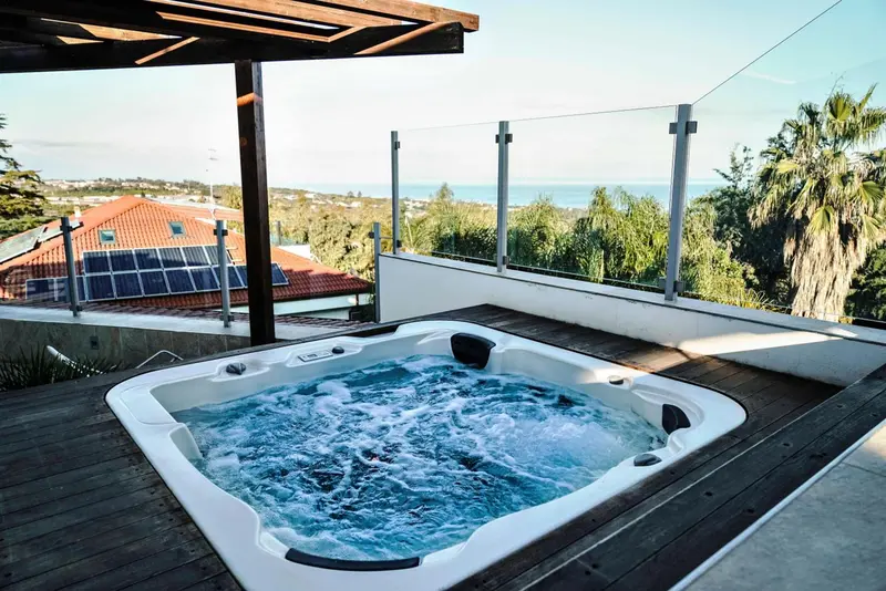 Un jacuzzi extérieur offre une vue dégagée sur la mer et la végétation environnante.
