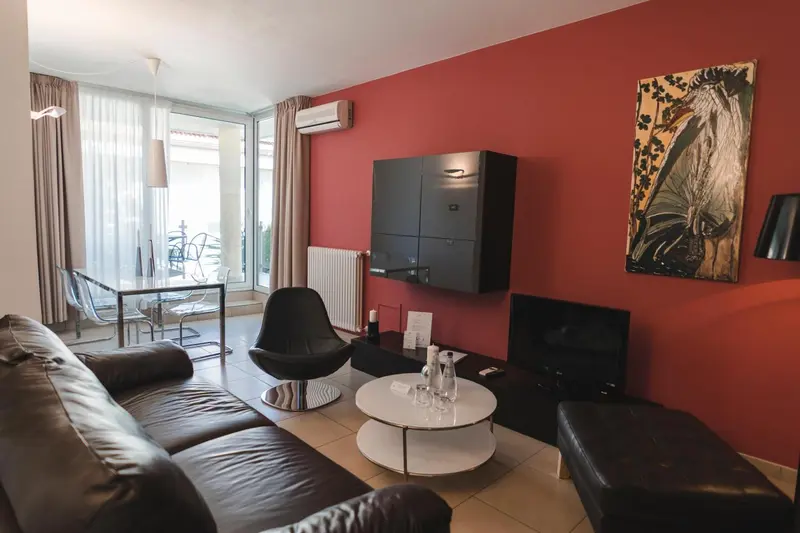 Un salon moderne avec canapé en cuir noir et tableau décoratif.