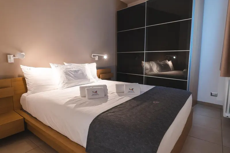 Une chambre lumineuse avec un grand lit recouvert d'une courtepointe blanche et grise.