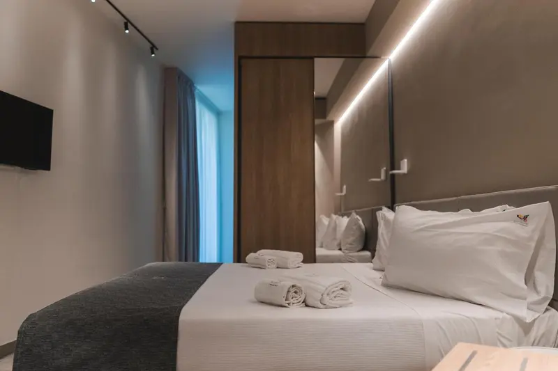 Une chambre avec un lit recouvert d'une courtepointe blanche et de coussins.