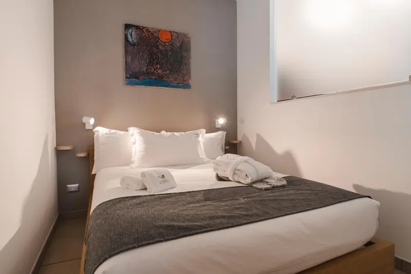 Une chambre avec un grand lit recouvert d'une couverture grise et de coussins blancs.
