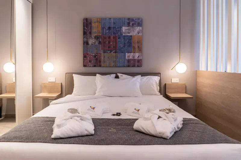 Une chambre avec un grand lit recouvert d'une couverture grise et de serviettes décoratives.