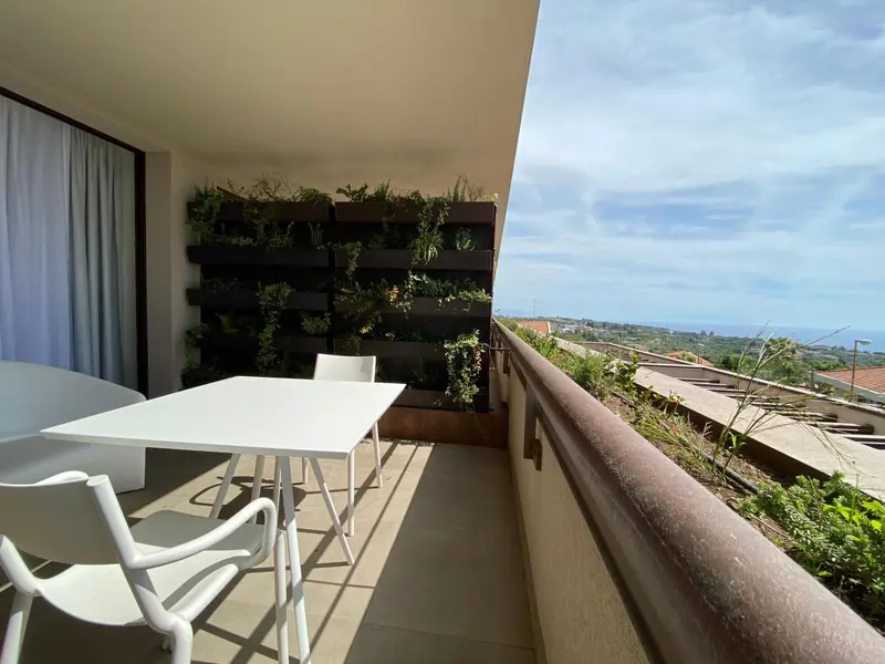 Terrasse aménagée avec table et chaises donnant sur un paysage verdoyant.