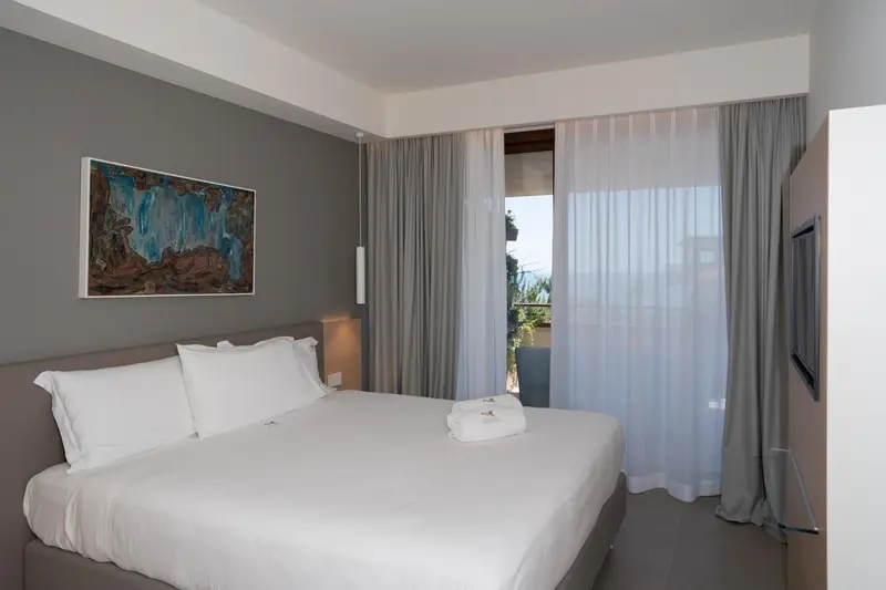 Une chambre lumineuse avec un grand lit et un accès à une terrasse.