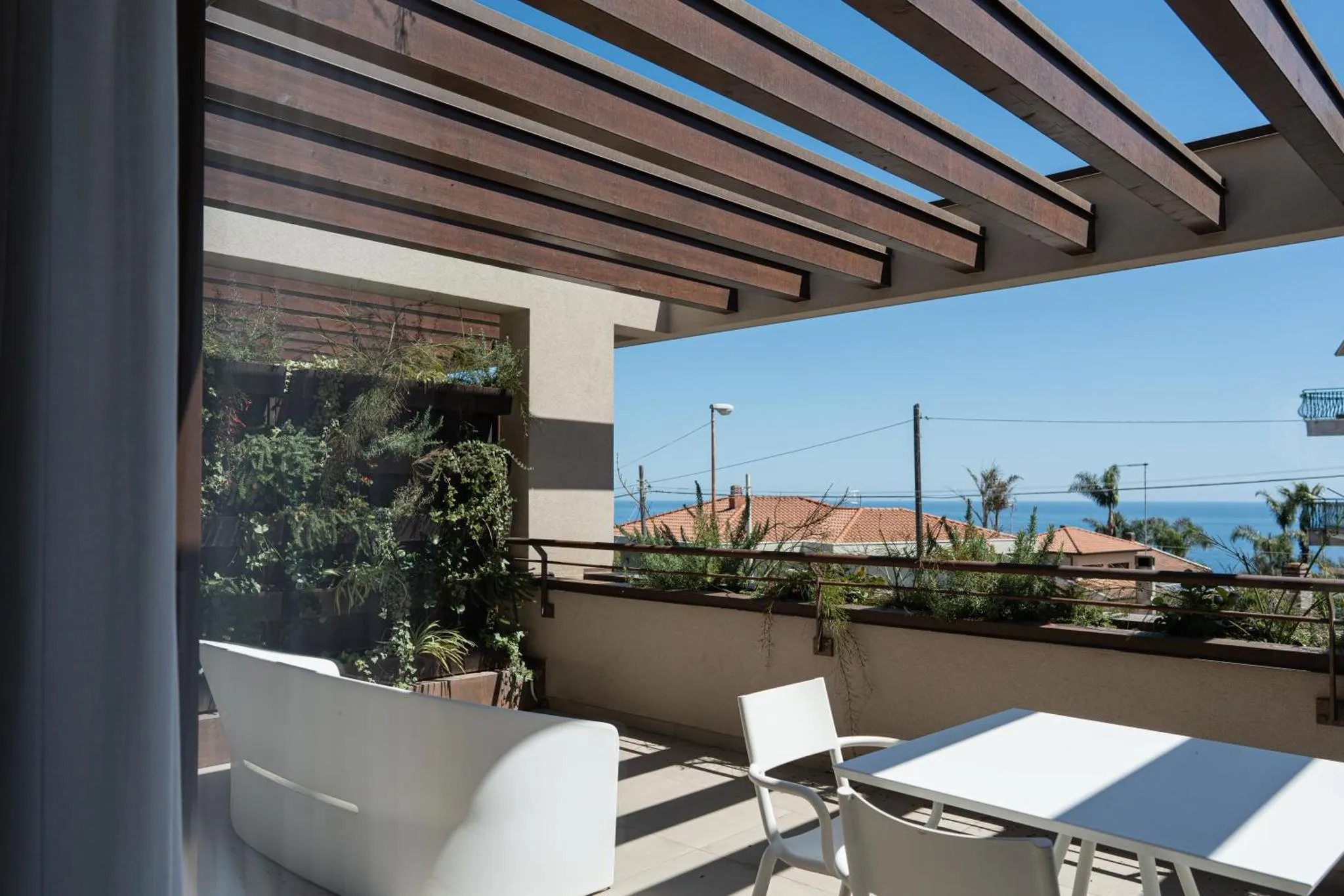 Terrasse ombragée avec mobilier blanc donnant sur la mer et le paysage.