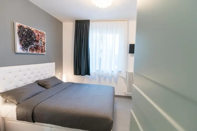 Une chambre moderne avec un grand lit et des rideaux blancs.
