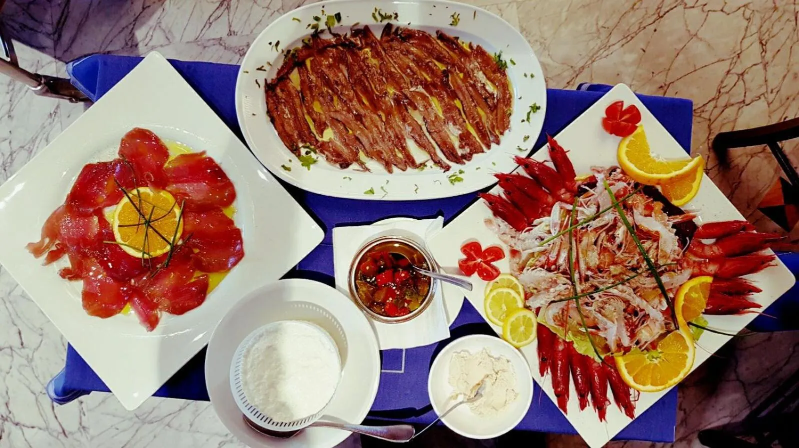 Assiettes de fruits de mer et de poissons décorées avec des légumes et des agrumes.