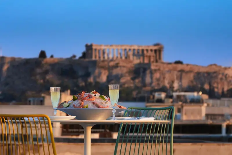 Une table dressée avec des fruits de mer et des coupes de champagne, avec une vue sur un site historique en arrière-plan.