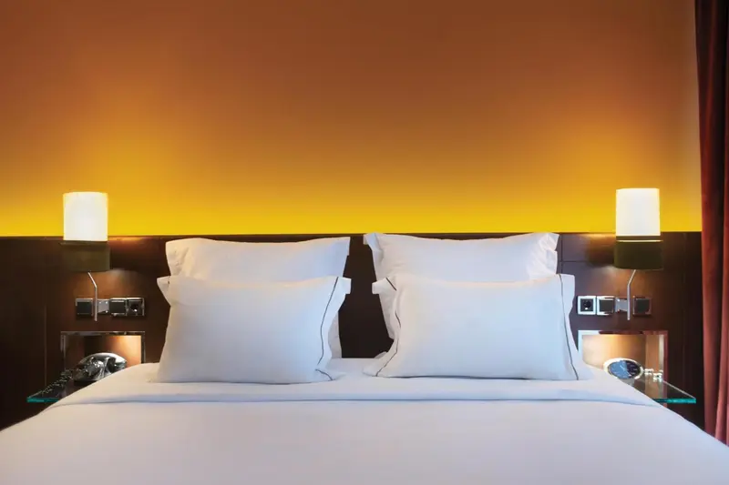Un lit double avec oreillers blancs dans une chambre moderne.