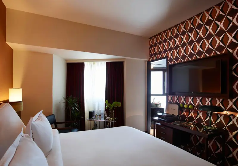Une chambre d'hôtel lumineuse avec un grand lit et un téléviseur mural.
