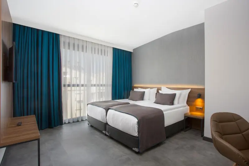 Chambre moderne avec deux lits simples et un fauteuil.